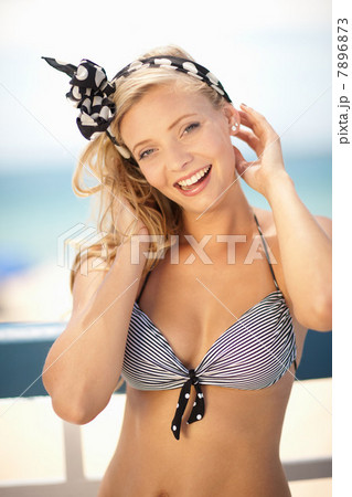 Smiling woman tying scarf in hair 7896873