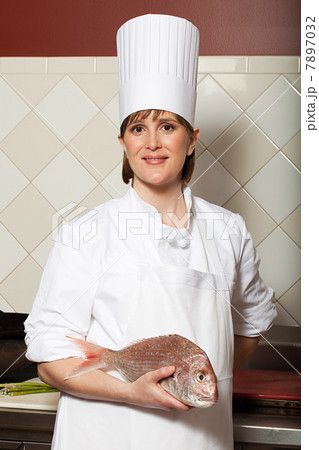 Female chef holding raw fish in commercial kitchen 7897032