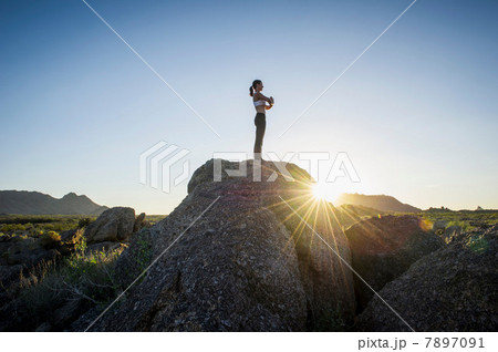Female standing on rock at sunrise Female standing on rock at sunrise 7897091