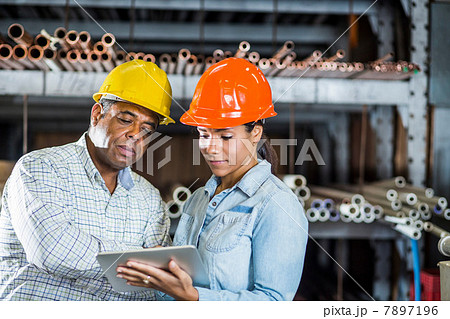 Man and woman in warehouse looking at digital tablet 7897196