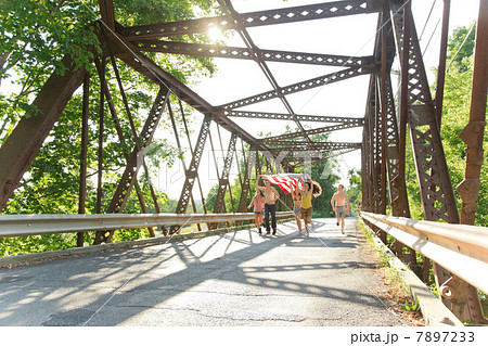 Group of friends running on bridge holding american flag Group of friends running on bridge holding american flag 7897233