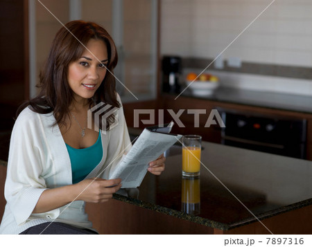 Woman reading newspaper at breakfast Woman reading newspaper at breakfast 7897316