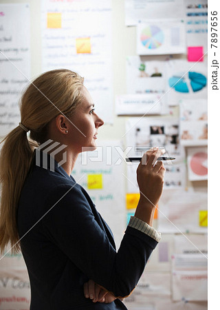 Contemplative woman holding pen 7897656