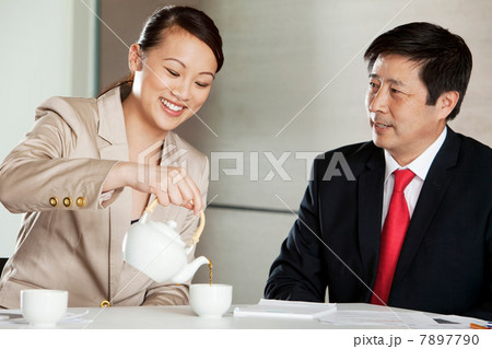 Businesswoman pouring tea for businessman 7897790