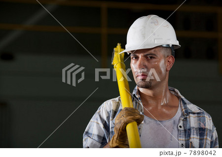 Mid adult construction worker wearing hard hat and holding tool, portrait 7898042