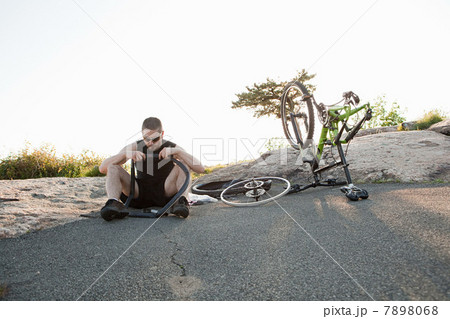 Male cyclist fixing punctured tyre Male cyclist fixing punctured tyre 7898068