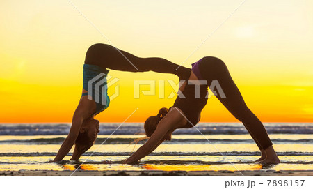 Women practicing yoga on beach 7898157