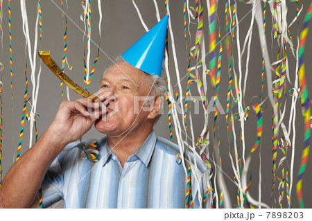 Senior man with party blower and streamers 7898203