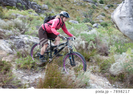 Young woman mountain biking through scrubland Young woman mountain biking through scrubland 7898217
