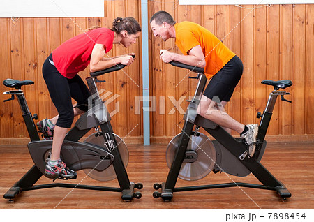 Man and woman competing against each other on exercise bikes 7898454