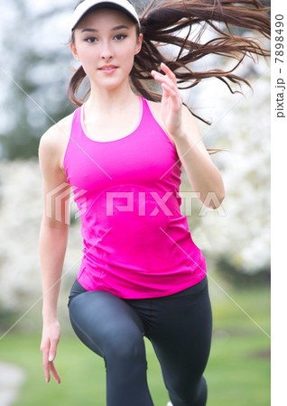 Teenage girl wearing pink sportswear running in park 7898490