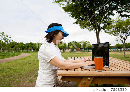 Woman using laptop on picnic bench in the park 7898539