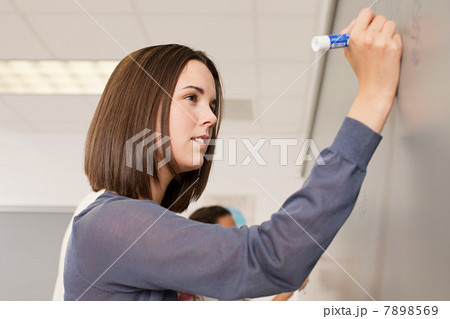 Female high school student writing on white board 7898569