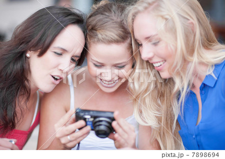 Three young women looking at photos Three young women looking at photos 7898694