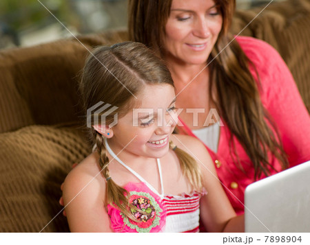 Mother and daughter using laptop on sofa 7898904