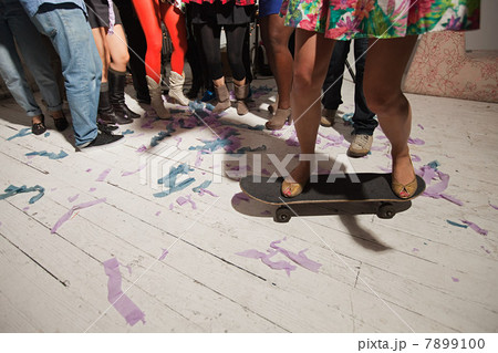 Woman standing on skateboard at party 7899100