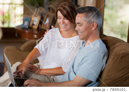 Couple using laptop together on sofa 7899101
