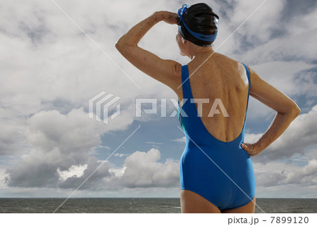 Senior woman wearing swimsuit looking towards sea, shielding eyes Senior woman wearing swimsuit looking towards sea, shielding eyes 7899120