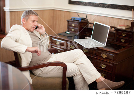 Mature man on cell phone sitting at desk 7899197