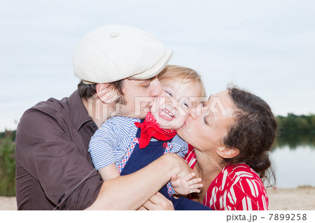 Couple kissing their young son on his cheeks 7899258