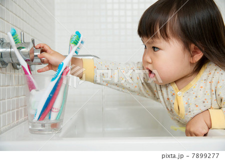 Close up of girl toddler turning bathroom sink taps 7899277