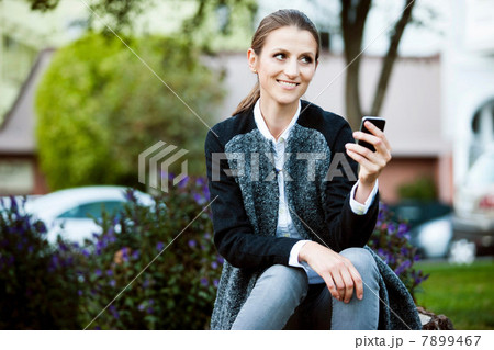 Woman using cell phone in urban park 7899467