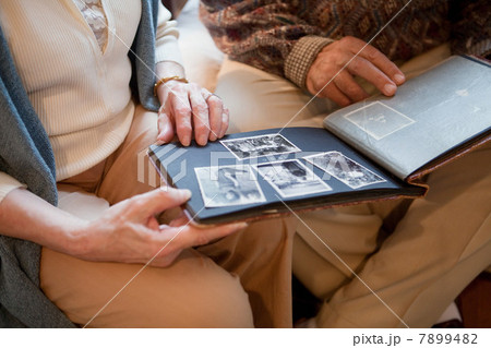 Senior couple looking through photo album, mid section Senior couple looking through photo album, mid section 7899482