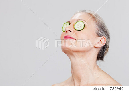Mature woman wearing cucumber slices over eyes, smiling Mature woman wearing cucumber slices over eyes, smiling 7899604