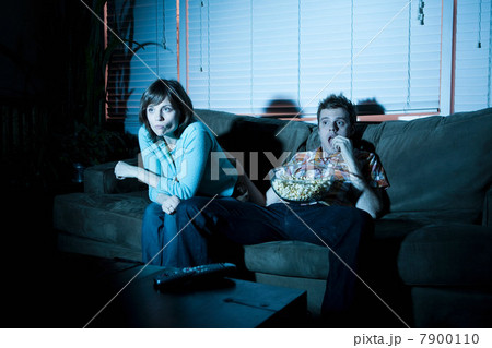 Young couple watching tv, man eating popcorn Young couple watching tv, man eating popcorn 7900110