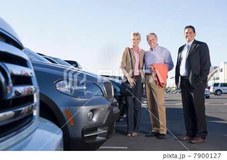 Portrait of three people with new cars at car dealership 7900127