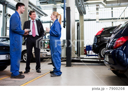 Businessman with two car mechanics in repair garage 7900208
