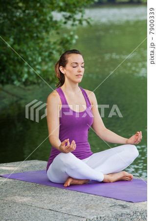 Mid adult woman performing yoga by river 7900339