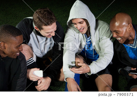 Soccer players looking at cellphone on pitch 7900371