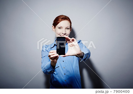Studio portrait of young woman holding up camera phone Studio portrait of young woman holding up camera phone 7900400