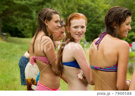 Girls in bikinis watching friends playing around in the country 7900588