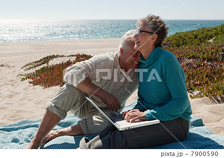 Mature couple using laptop at the beach Mature couple using laptop at the beach 7900590