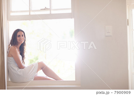 Young woman wearing sundress by window Young woman wearing sundress by window 7900909