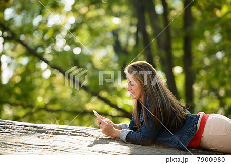 Woman using cell phone in park 7900980