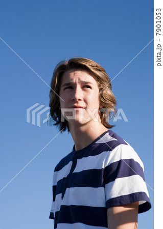 Teenage boy wearing blue and white striped t shirt against blue sky, portrait Teenage boy wearing blue and white striped t shirt against blue sky, portrait 7901053