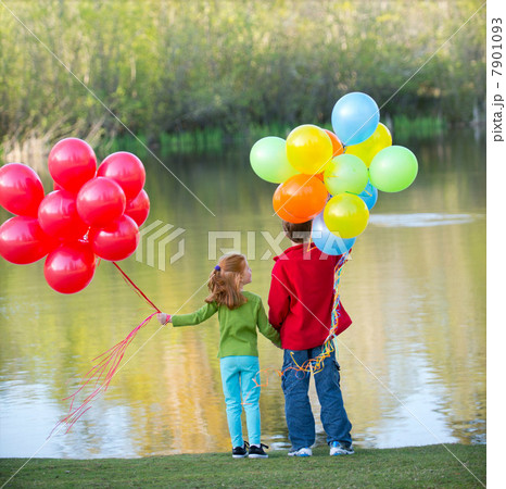 Brother and sister holding balloons in park 7901093