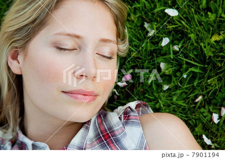 Young woman lying on grass with eyes closed 7901194