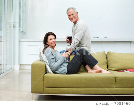 Mature couple sitting on sofa with wine 7901460