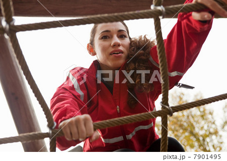 Young woman climbing assault course equipment 7901495