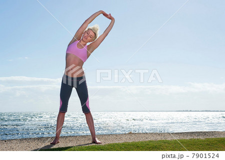 Young woman stretching by sea Young woman stretching by sea 7901524
