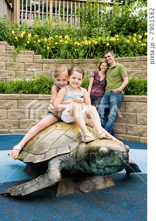 Two girls sitting on top of tortoise statue at the zoo 7901562