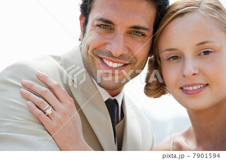Bride wearing wedding ring with hand on groom's shoulder 7901594