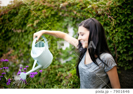 Young woman watering flowers in garden 7901646