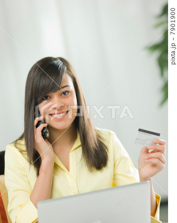 Young woman using credit card over the phone, portrait 7901900