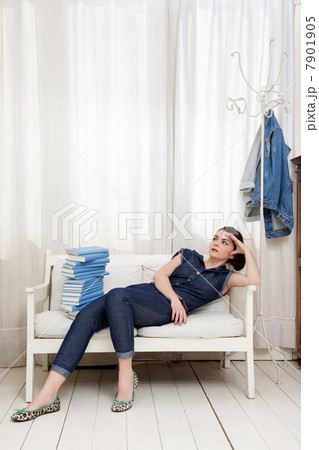 Woman reclining on seat with pile of books 7901905