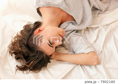Young woman lying on bed, looking away 7902180